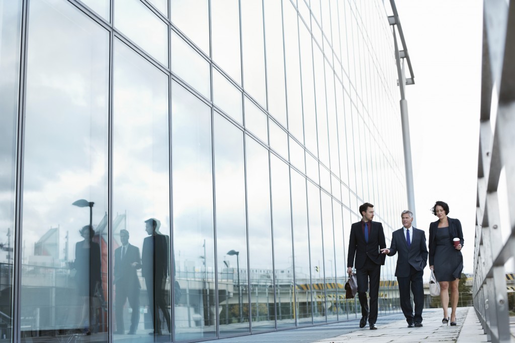 Professionals walking alongside glass building